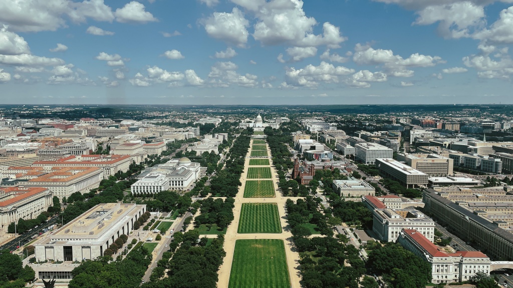 Taken from the top of the Washington Monument in Washington D.C. The national mall is centered in the image and leading towards the Capitol Building in the distance. It is a bright and sunny day.
